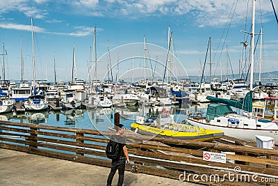 A Chinese tourist looking at a lot of yachts parking in harbor at the Fisherman`s Wharf Pier 39 marina in San Francisco, Editorial Stock Photo