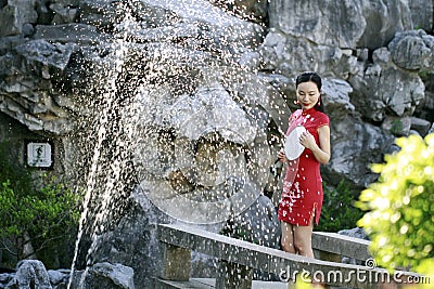 Chinese woman in cheongsam by a fountain in Mudu ancient town Stock Photo