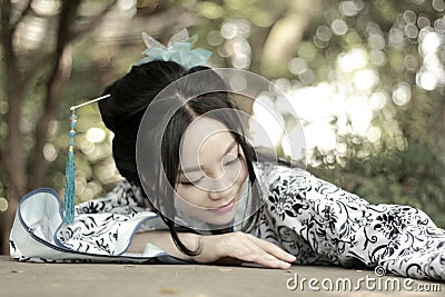 Chinese woman in traditional Blue and white Hanfu dress Climb over the stone table Stock Photo