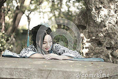 Chinese woman in traditional Blue and white Hanfu dress Climb over the stone table Stock Photo