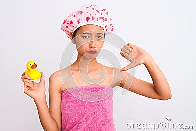 Chinese woman wearing shower towel and cap holding duck toy over isolated white background with angry face, negative sign showing Stock Photo