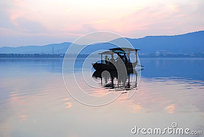 Chinese wooden boat drifting on a lake in sunset Stock Photo
