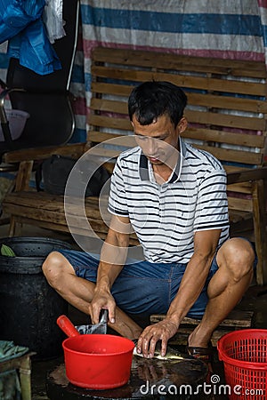 Chinese person peeling skin off small fish Editorial Stock Photo