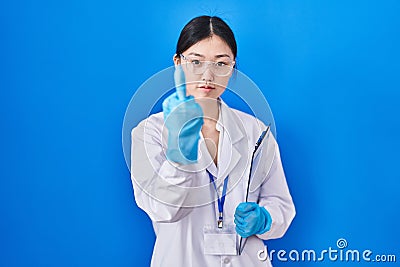Chinese young woman working at scientist laboratory showing middle finger, impolite and rude fuck off expression Stock Photo