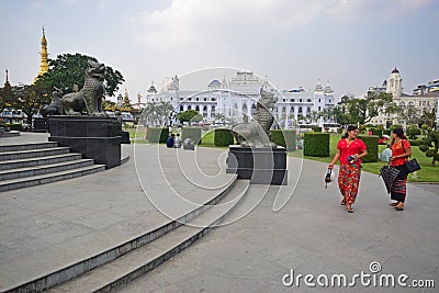 Chinthe Statues in Yangon Myanmar with beautiful women in Red in front & temple & colonial buildings in the background Editorial Stock Photo