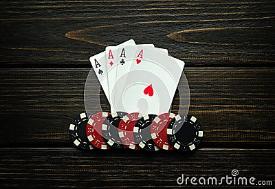 Chips and playing cards with a winning combination of four of a kind or quads on a black vintage table. Concept of winning in a Stock Photo