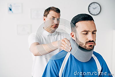 Chiropractor examining good-looking football player in neck brace Stock Photo