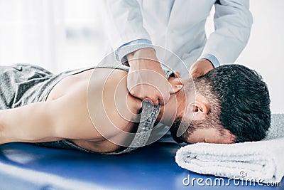Chiropractor massaging neck of man lying on Massage Table Stock Photo