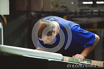 CHISINAU, MOLDOVA - APRIL 26, 2016: Workers in printing house. People working on printing machine in print factory. Industrial wor Editorial Stock Photo