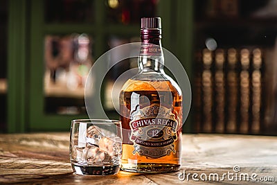 Chivas Regal whiskey bottle and glass with ice cubes on wooden t Editorial Stock Photo