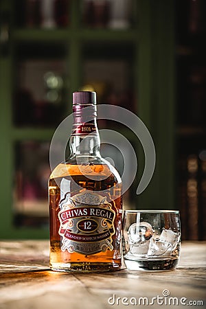 Chivas Regal whiskey bottle and glass with ice cubes on wooden t Editorial Stock Photo