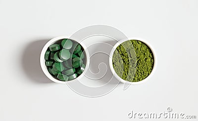 Chlorella and spirulina. Spirulina pills and chlorella green powder on a white background. Mineral food additive. Top view, flat Stock Photo