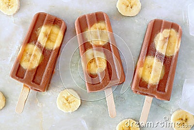 Chocolate banana popsicles on white marble Stock Photo