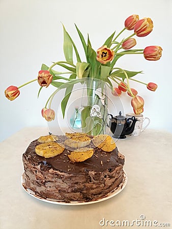 Chocolate cake decorated with oranges on the background of tulips Stock Photo