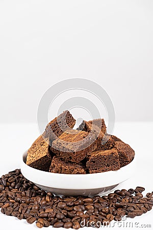 Chocolate cake sliced into squares in a white plate, brownie and coffee beans, space for text Stock Photo