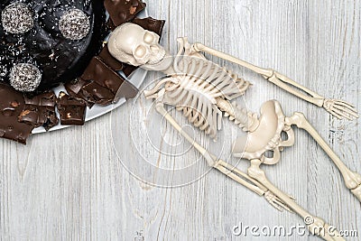 Chocolate cake and slices on a plate and skeleton on a wooden table. Concept of death from diabetes Stock Photo