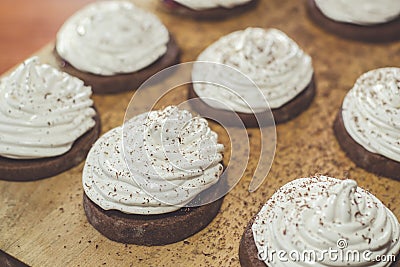 Chocolate cakes with egg white cream on the wooden board. Sweet and tasty homemade food Stock Photo