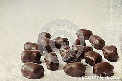 Chocolate candies. Dark chocolates with natural plum filling. Old paper textured image Stock Photo