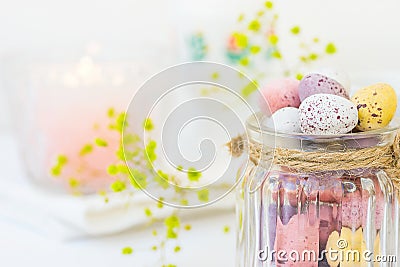 Chocolate Candy Multi-Colored Small Quail Easter Eggs Pastel Colors in Vintage Glass Jar on White Wood Table Yello Flowers Stock Photo