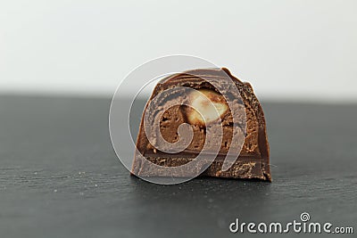Chocolate candy with whole walnut forest hazelnuts with praline chocolate filling in section on a dark black background with space Stock Photo