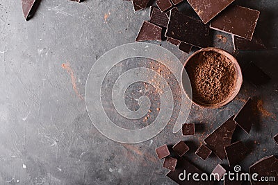 Chocolate chunks and cocoa powder. Chocolate bar pieces. A large bar of chocolate on gray abstract background. Stock Photo