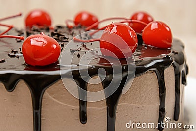 Chocolate covered cake decorated with coctail cherries. Stock Photo