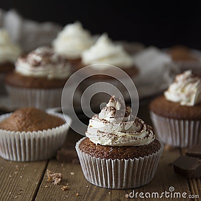 Chocolate cupcakes with whipped cream on rustic wooden table. Homemade dessert. Square image Stock Photo