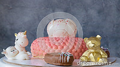And chocolate decorations teddy bear. unicorn, lamb and popsicle. Pink mousse bagel cake in circles with white chocolate peony on Stock Photo