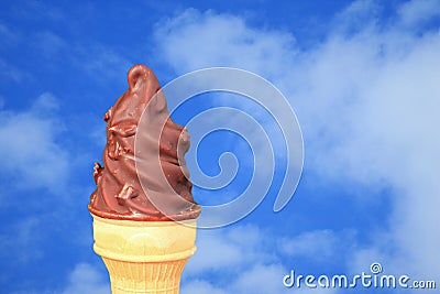 Chocolate Dipped Soft Serve Ice Cream Cone Against Vivid Blue Sky with White Cloud Stock Photo