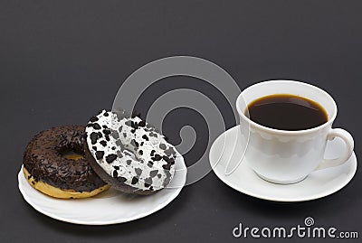 Chocolate donuts and coffee. Two beautiful tasty donuts on a saucer and a cup of aromatic hot coffee Stock Photo