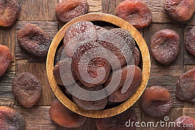 Chocolate dried apricots in wooden bowl, top view Stock Photo