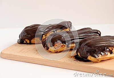 Chocolate eclair on wooden desk food photography. Bekery, cake , choco, pie, confectionary, cream. Three fresh eclairs with chocol Stock Photo