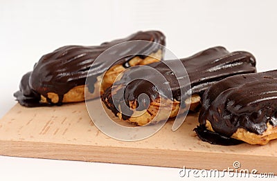 Chocolate eclair on wooden desk food photography. Bekery, cake , choco, pie, confectionary, cream. Three fresh eclairs with chocol Stock Photo