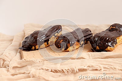 Chocolate eclair on wooden desk food photography. Bekery, cake , choco, pie, confectionary, cream. Three fresh eclairs with chocol Stock Photo