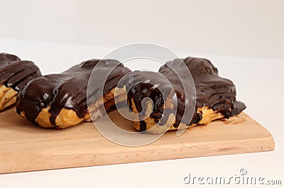Chocolate eclair on wooden desk food photography. Bekery, cake , choco, pie, confectionary, cream. Three fresh eclairs with chocol Stock Photo
