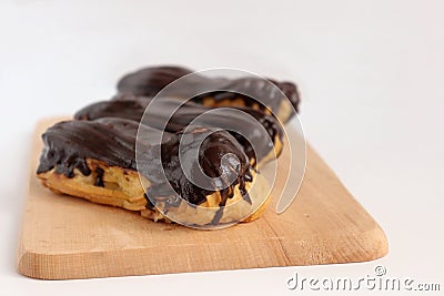 Chocolate eclair on wooden desk food photography. Bekery, cake , choco, pie, confectionary, cream. Three fresh eclairs with chocol Stock Photo