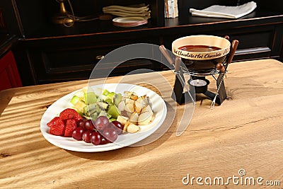 Chocolate fondue with fruits assortment on wooden background Stock Photo