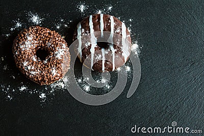 Chocolate and glazed donuts, white, brown on black stone, top view Stock Photo