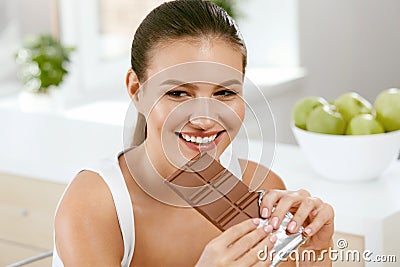 Chocolate. Happy Woman Biting Chocolate Bar. Stock Photo