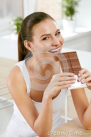 Chocolate. Happy Woman Biting Chocolate Bar. Stock Photo