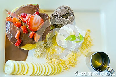 Chocolate ice-cream with strawberry, whip cream served with banana, chocolate filled crepe and natural honey Stock Photo