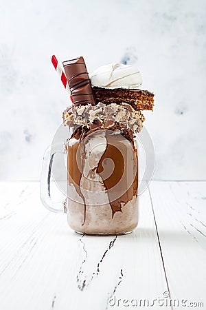 Chocolate indulgent exreme milkshake with brownie cake, marshmallow and sweets. Crazy freakshake food trend. Stock Photo