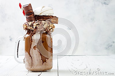 Chocolate indulgent extreme milkshake with brownie cake, marshmallow and sweets. Crazy freakshake food trend. Stock Photo