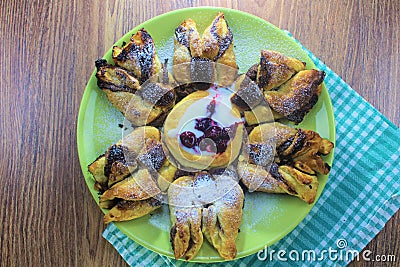 Chocolate nugget puff pastry flower with the vanilla sauce and sour cherry covered with powdered sugar, green and brown wooden bac Stock Photo