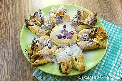 Chocolate nugget puff pastry flower with the vanilla sauce and sour cherry covered with powdered sugar, green and brown wooden bac Stock Photo