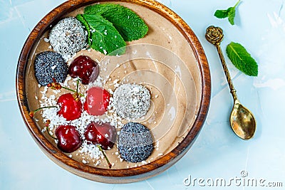 Chocolate smoothie bowl with cherry, mint and energy balls. Stock Photo