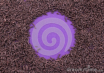 Chocolate sprinkles covering a purple background leaving a circle in centre for text Stock Photo