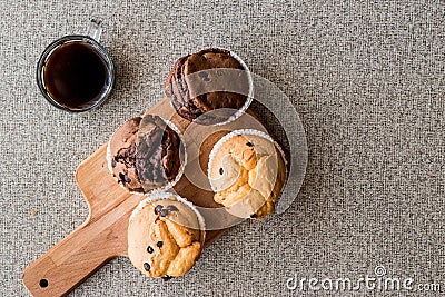 Chocolate and Vanilla Muffins with coffee on wooden surface. Stock Photo