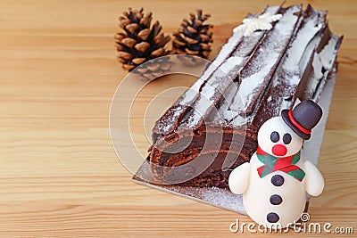 Chocolate Yule Log Cake for Christmas or Buche de Noel with a Cute Snowman Marzipan and Two Dry Pin Cones Stock Photo