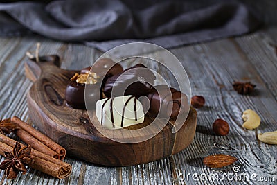 Chocolates in different shapes and colors over rustic wooden board. Stock Photo